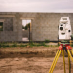 Surveyor equipment - GPS system or theodolite total positioning system outdoors at house construction site. Surveyor engineering with total station before house building